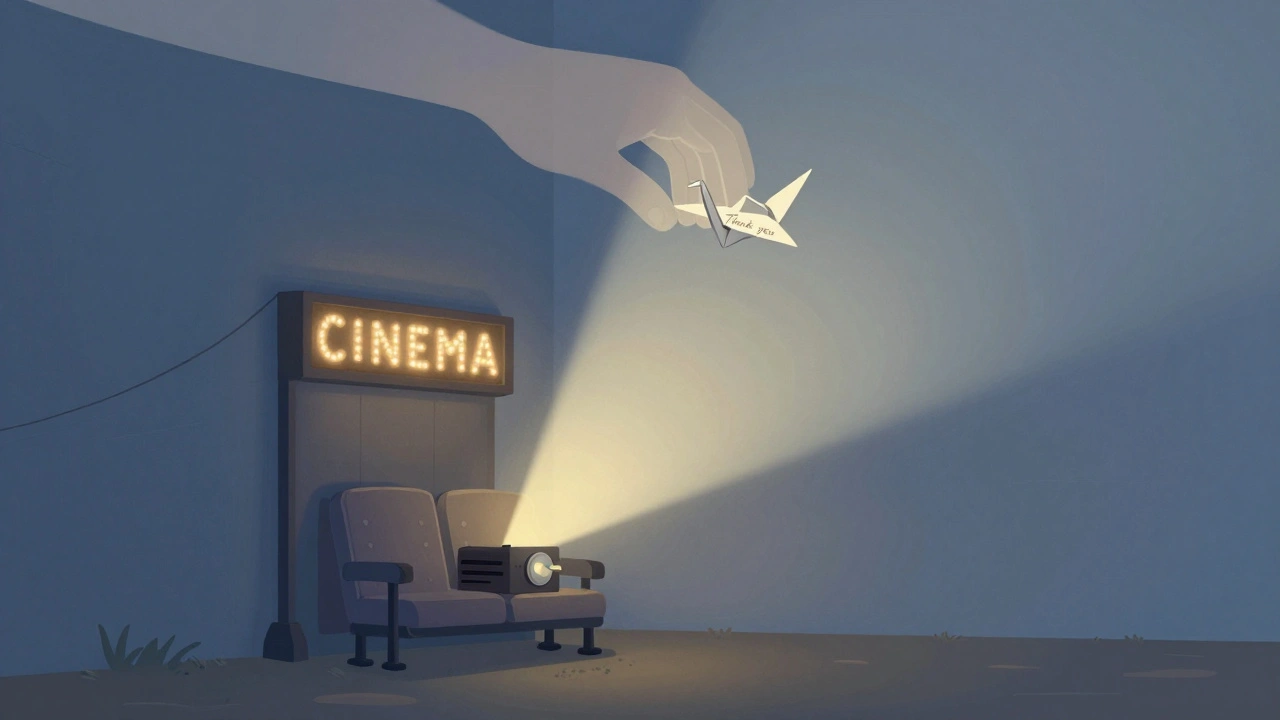 A quiet Irish cinema at dusk with a projector beam and a paper crane above an empty seat.